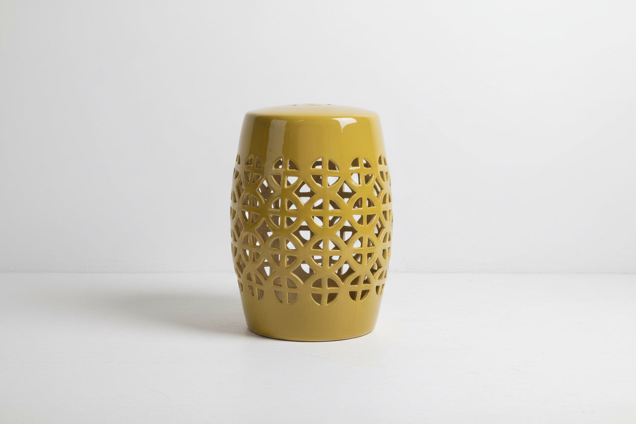 Yellow ceramic stool with intricate lattice design on a white background