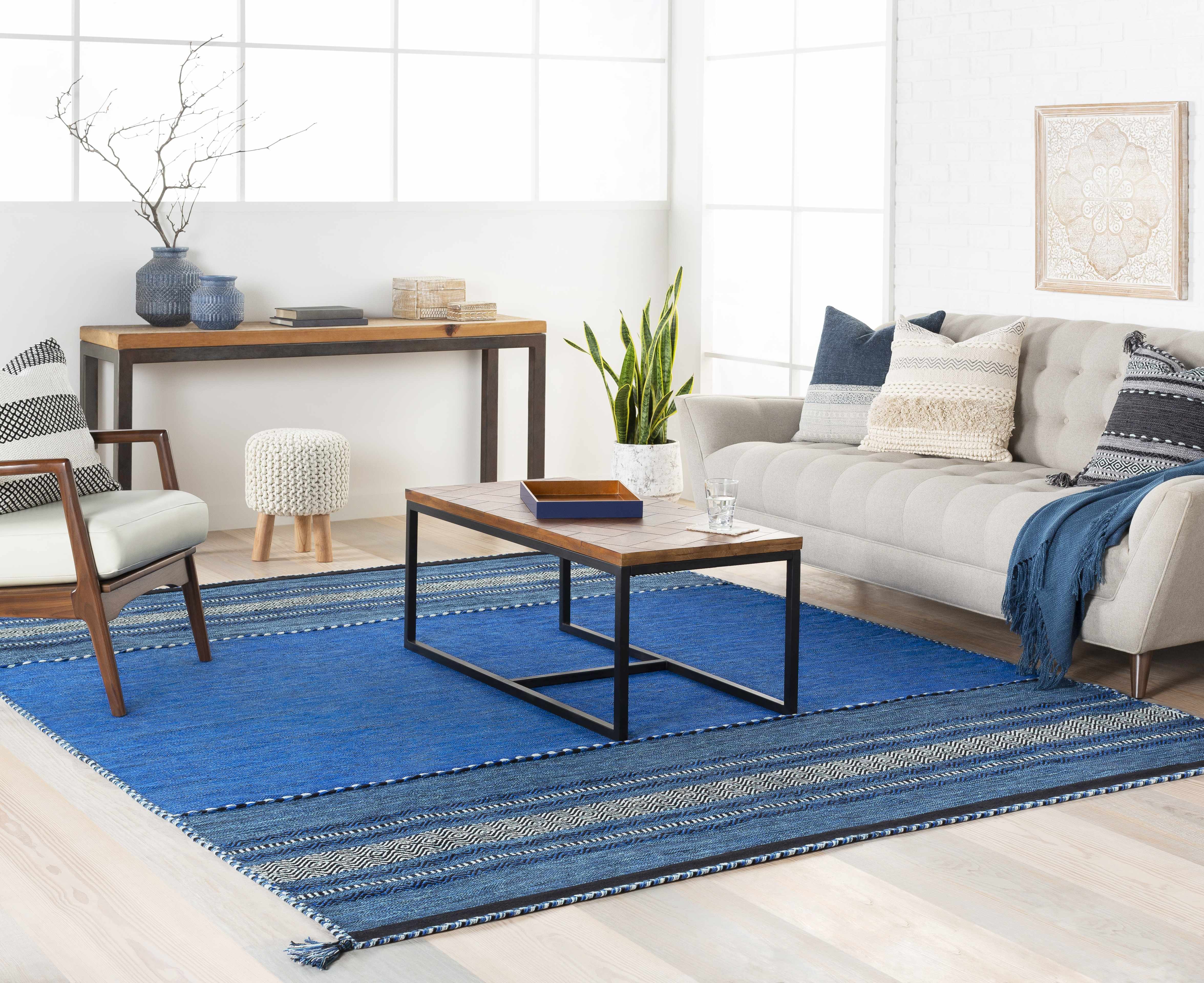Living room with a blue rug, gray sofa, and wooden coffee table.