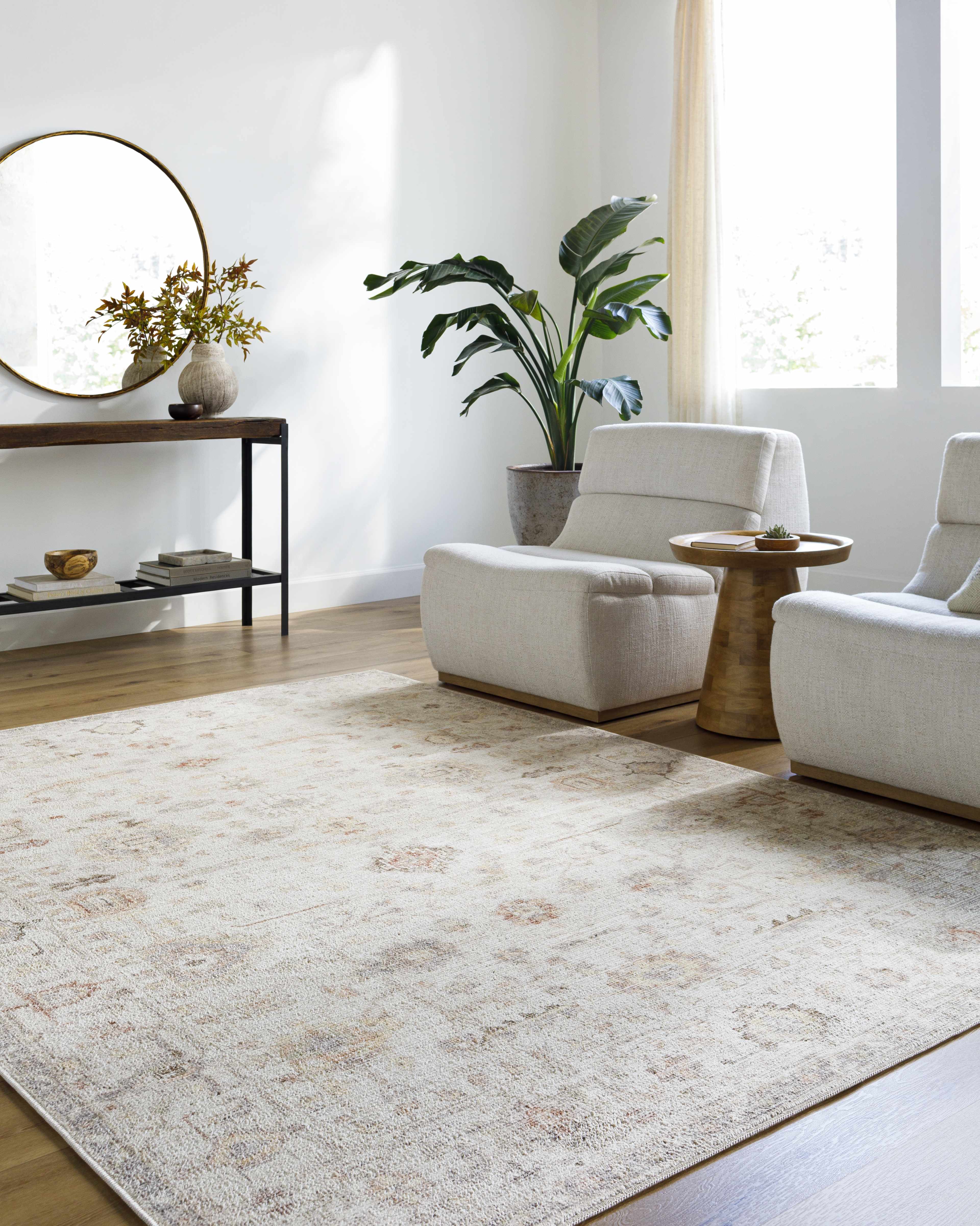 Modern living room with white chairs, a patterned rug, and decorative elements.