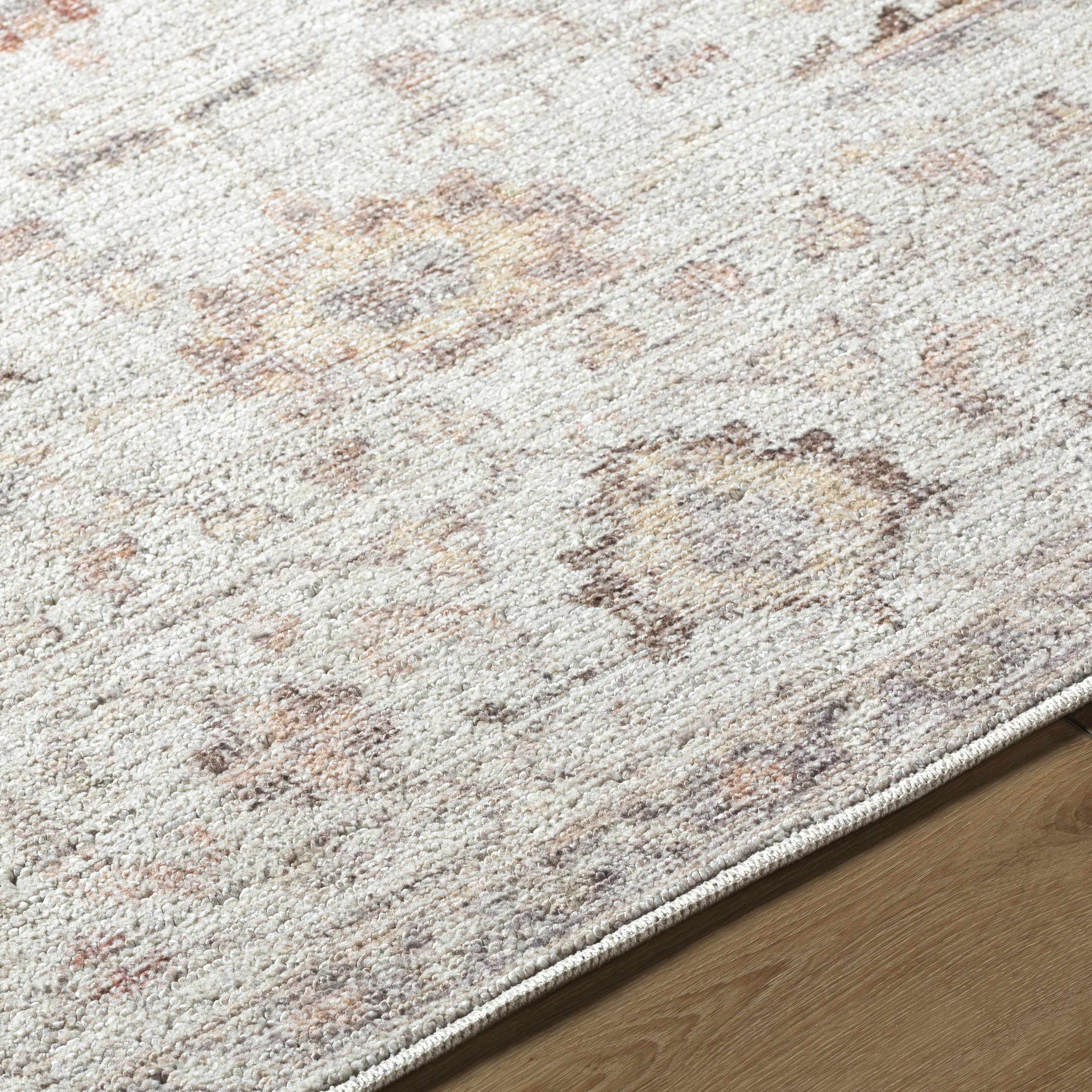 Close-up of a textured area rug with a neutral color palette on a wooden floor.